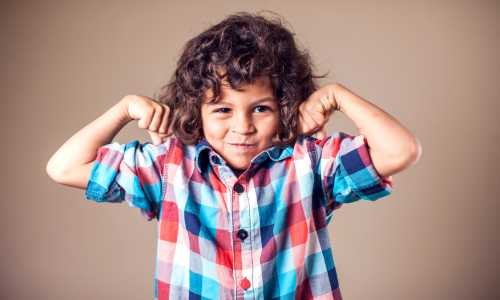 Jongen met krullen laat trots zijn spierballen zien: je hoogsensitieve kind traint zijn binnenwereld en gevoelens