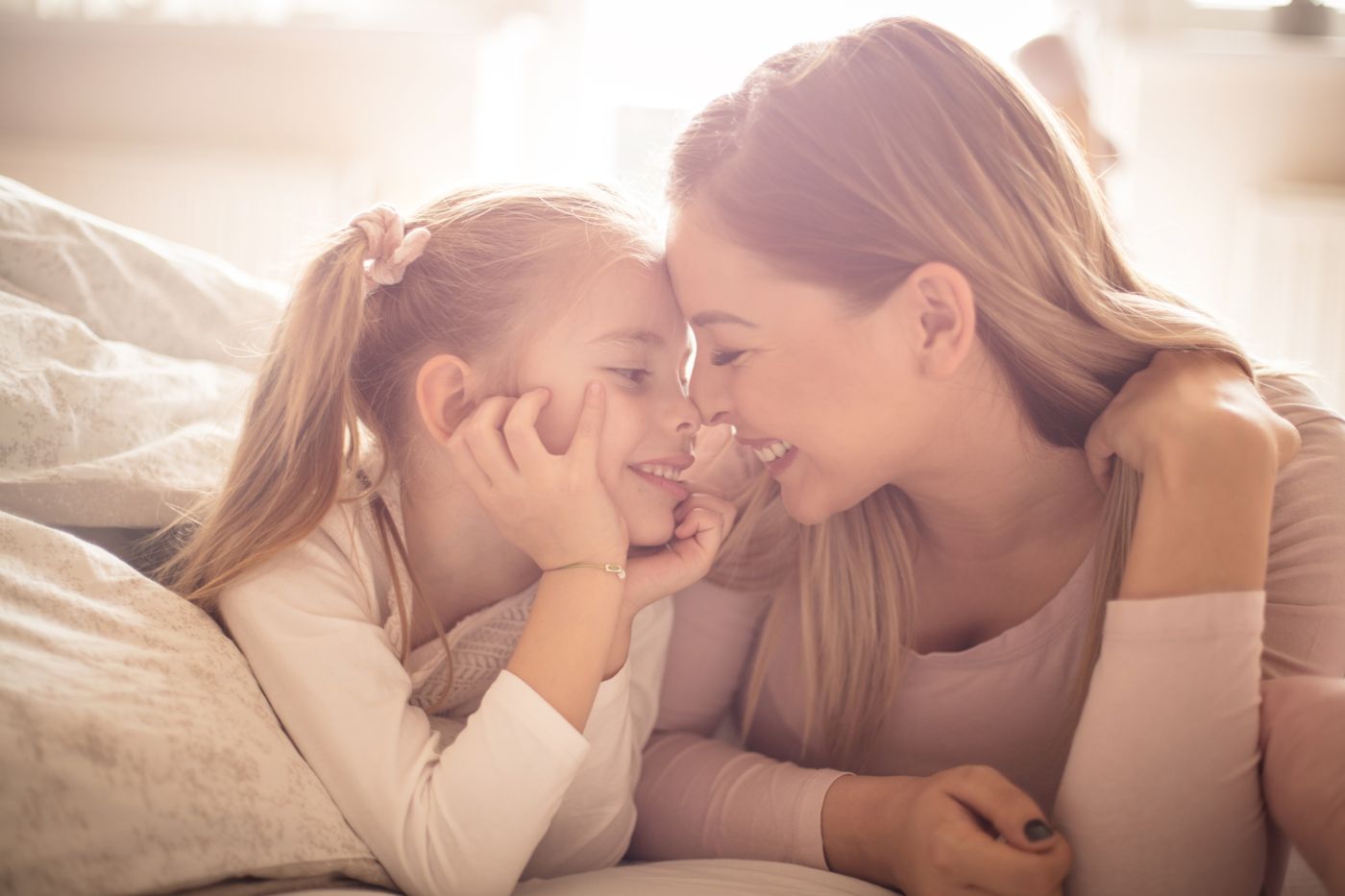 Moeder en dochter liggen neus aan neus op bed: connectie en veiligheid voor het slapengaan