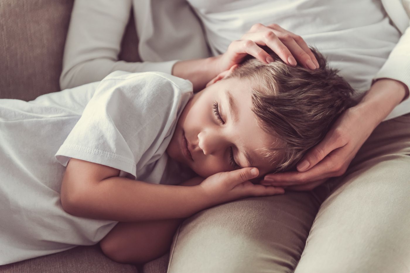 Ouder legt een hand op het hoofd van een slapende jongen: een slaapassociatie waar een kind aan gewend raakt