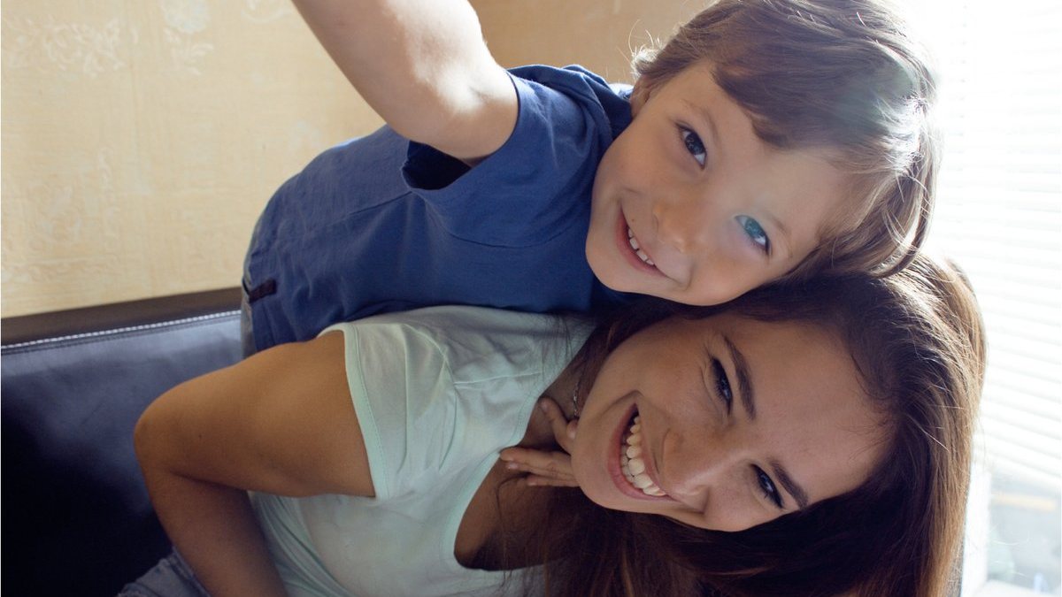Lachende moeder met haar strong-willed kind op haar rug: intens lief en wild tegelijk