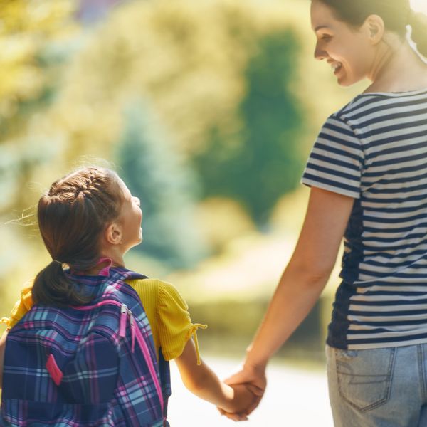 Moeder en dochter lopen hand in hand buiten in het groen