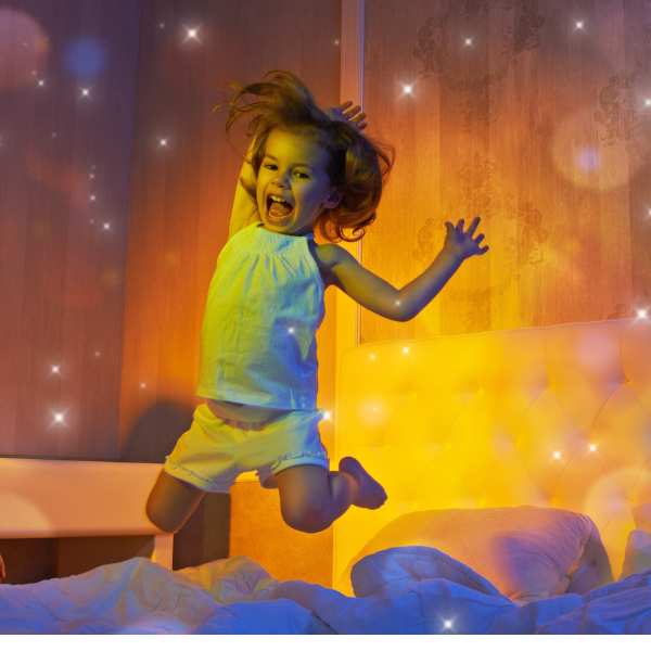 Kind springt vol energie op bed rond bedtijd, in warm avondlicht