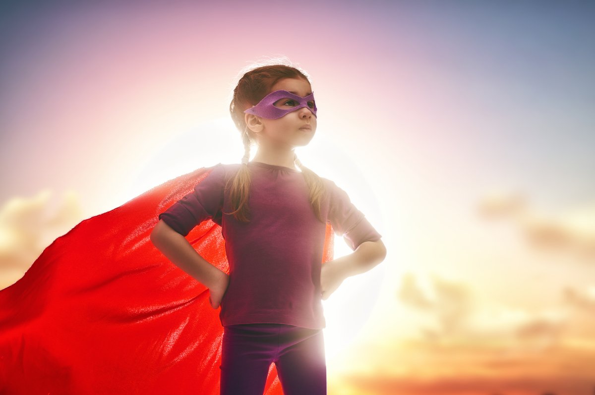 Kind met superheldenmasker en rode cape, vastberaden en vol intense energie